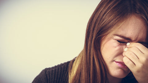 Woman holds bridge of nose with a pained expression on her face