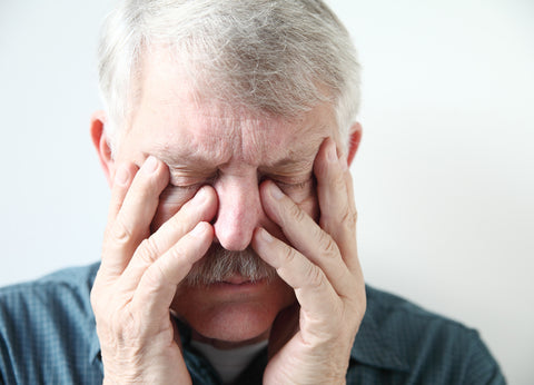 An older man holds the sides of his face with a pained expression