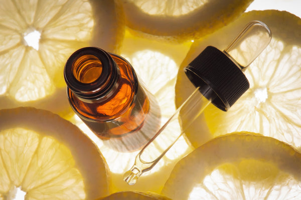 A close-up shot of an amber-colored bottle and dropped sitting on top of lemon slices