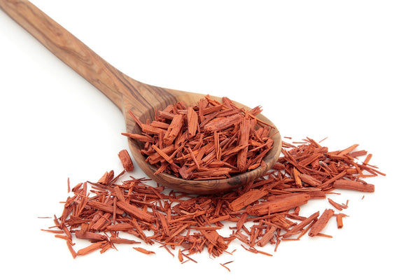 A wooden spoon filled with and surrounded by sandalwood